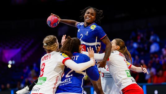 Eine französische Hanball Nationalspielerin setzt sich kraftvoll im Sprungwurf gegen die Abwehr durch.