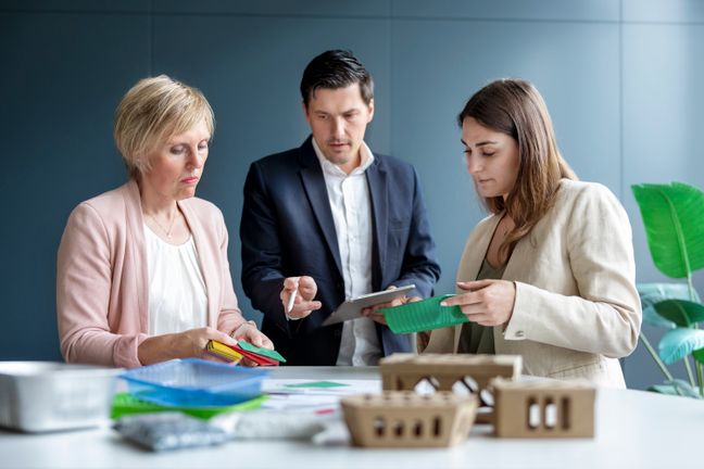 Drei Experten begutachten verschiedene Materialproben und Verpackungen.