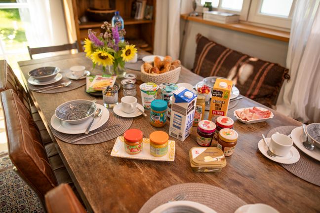 Ein reichhaltig gedeckter Frühstückstisch mit veganen Produkten, frischen Blumen und Vollkorngebäck.