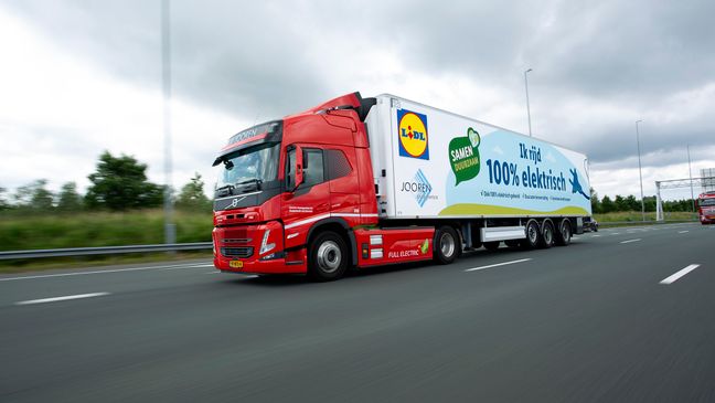 Auf der Autobahn fährt ein E-Lkw von Lidl dynamisch und zügig unter bewölktem Himmel.