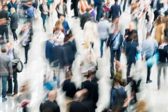 Zahlreiche Menschen bewegen sich geschäftig durch eine helle Halle und verdeutlichen die Dynamik gesellschaftlicher Ziele.