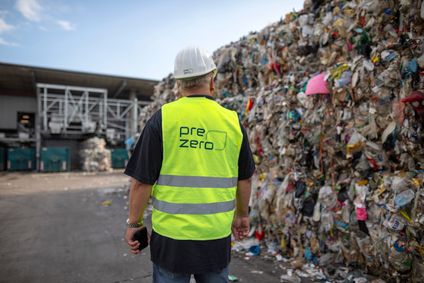 Ein PreZero-Mitarbeiter blickt auf eine riesige Wand aus gepressten Wertstoffballen in einer Recyclinganlage.