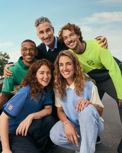 Fünf lächelnde, diverse Lidl-Kollegen in Arbeits- und Freizeitkleidung symbolisieren Teamgeist unter blauem Himmel.