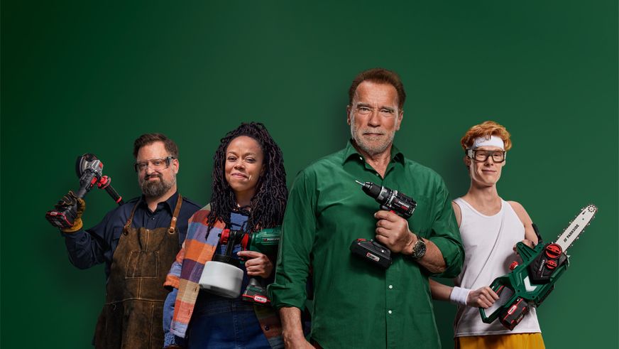 Arnold Schwarzenegger und ein diverses Team präsentieren stolz verschiedene Parkside Werkzeuge vor grünem Hintergrund.