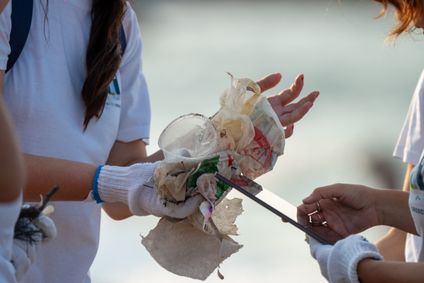 Detaillaufnahme von sammeln Plastikmüll an einem Strand und dokumentieren die Funde auf einem Tablet.
