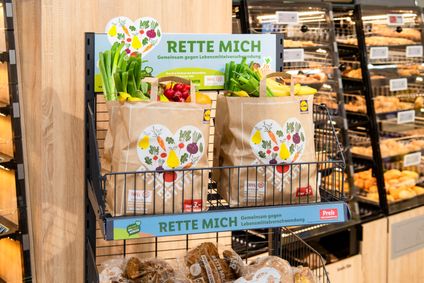 Zwei prall gefüllte Rettertüten mit Obst und Gemüse stehen verkaufsbereit im Regal für Lebensmittelrettung.