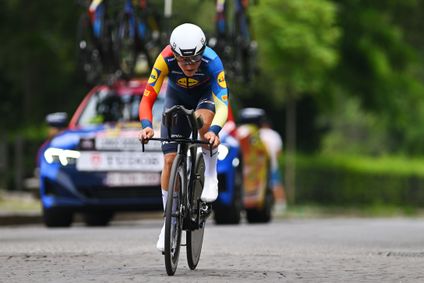Ein Lidl-Trek Radsportlerin fährt in aerodynamischer Position auf einer gepflasterten Straße, im Hintergund ein Catcher Car.