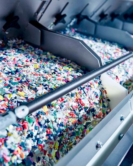 Buntes Kunststoff-Granulat läuft in einer Sortieranlage über Förderbänder für effizientes Ressourcen-Recycling.