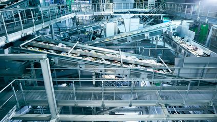Zahlreiche Förderbänder transportieren Wertstoffe durch eine moderne, großflächige Recycling-Sortieranlage.