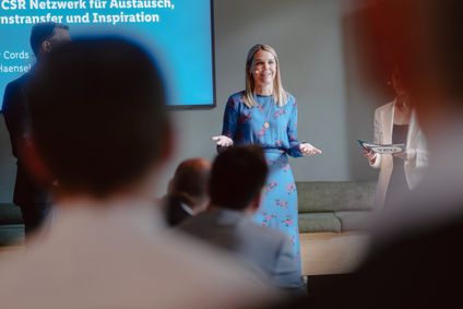 Eine Sprecherin der Mitarbeiterinitiative YOU spricht leidenschaftlich vor dem Team.