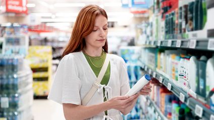 Kundin liest vor einem Supermarktregal die Hinweise eines Körperpflegeproduktes.