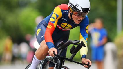 Seitliche Nahaufnahme einer konzentrierten Lidl-Trek Radsportlerin in tiefer Aero-Position mit Helm und verspiegeltem Visier.