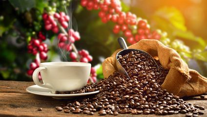 Cup of coffee with smoke and coffee beans in burlap sack on coff