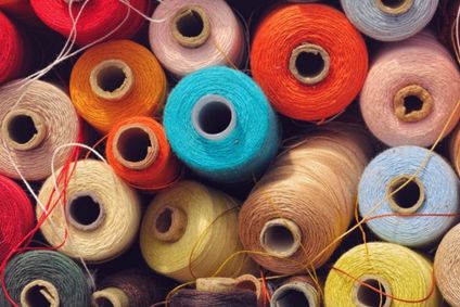 Vielfältige bunte Garnrollen liegen dicht gestapelt beieinander.