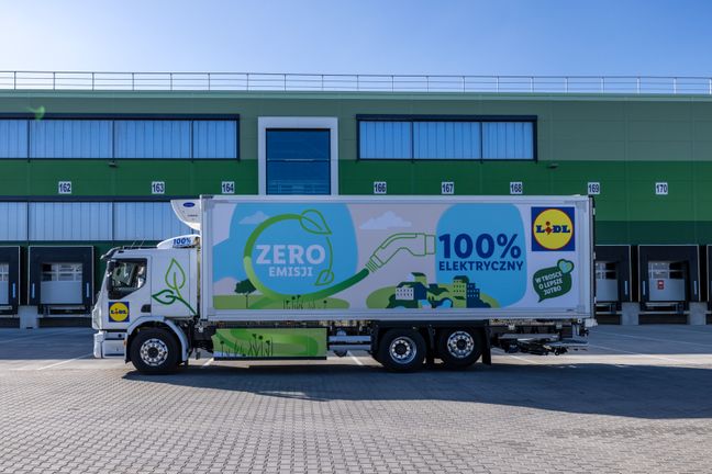 Ein neuer Lkw für E-Mobilität bei Lidl parkt mit "100% elektrisch"-Aufschrift sauber vor den Toren eines Logistikzentrums.