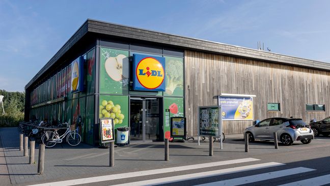 Moderne Lidl Filiale mit einer Fassade aus hellem Holz, Solarpaneelen auf dem Dach und Fahrradständern im Vordergrund.