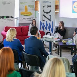 Panelistica s mikrofonom govori sudionicima na edukativnom predavanju o celijakiji i bezglutenskoj prehrani.