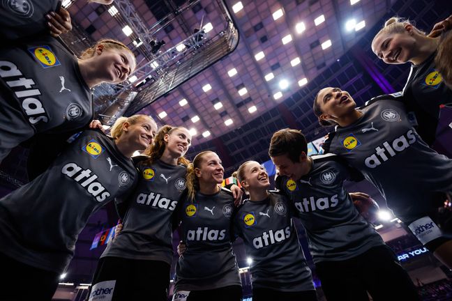 Froschperspektive in den Teamkreis der lächelnden deutschen Handball-Nationalmannschaft der Frauen.