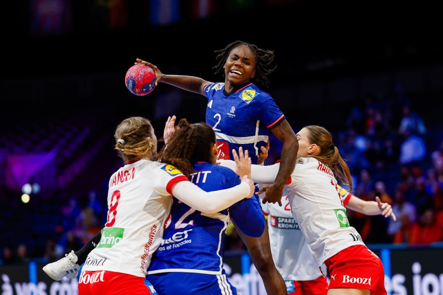 Eine französische Hanball Nationalspielerin setzt sich kraftvoll im Sprungwurf gegen die Abwehr durch.