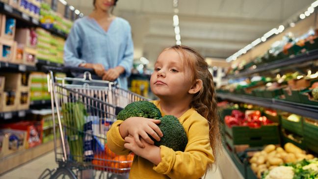 bimba al supermercato con in mano broccoli