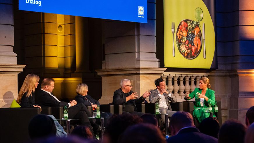 Blick aus dem Zuschauerraum auf die Bühne, auf welcher vier Experten in Sesseln über verantwortungsvolle Unternehmensführung debattieren.