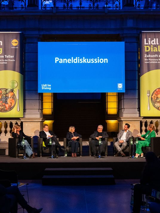 Sechs Experten im Austausch auf einer Bühne einer Paneldiskussion im Rahmen der Reihe „Lidl im Dialog“.