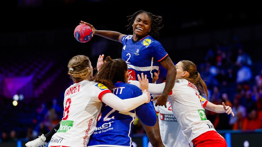 Eine französische Hanball Nationalspielerin setzt sich kraftvoll im Sprungwurf gegen die Abwehr durch.