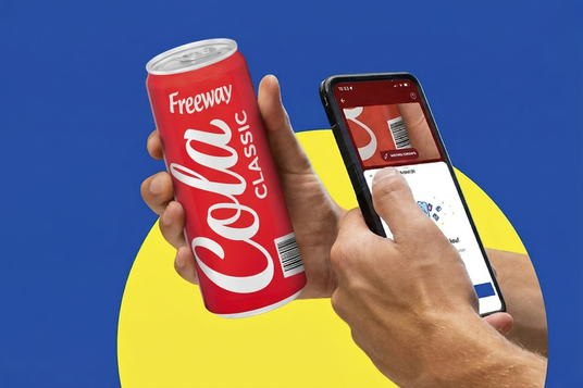 Hände in Nahaufnahme scannen eine Freeway Cola-Dose mit dem Smartphone via Scan & Go an einer Lidl Self-Checkout-Kasse.