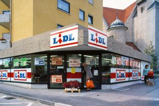 Aufnahme der Außenfassade des ersten Lidl-Marktes mit Retrologos und handgeschriebenen Preisschildern.