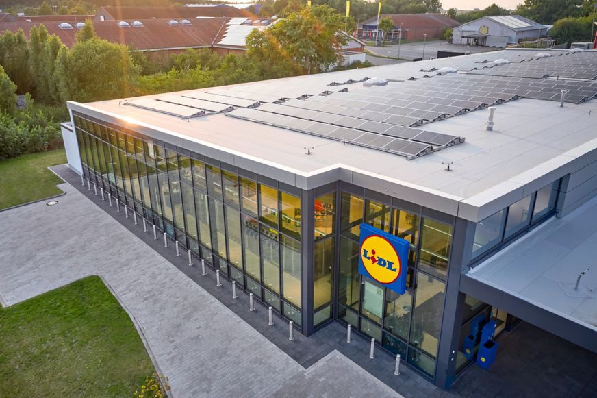 Pogled iz zraka na modernu trgovinu Lidl sa solarnim panelima postavljenim na krovu.