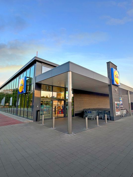 Moderne Lidl Holzbaufiliale mit großer Glasfront und Holzverkleidung im hellen Abendlicht.
